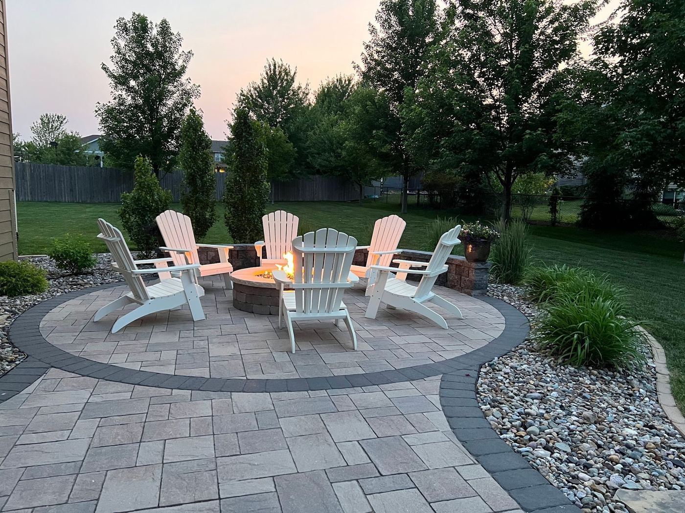Round paver fire pit area with chairs at dusk